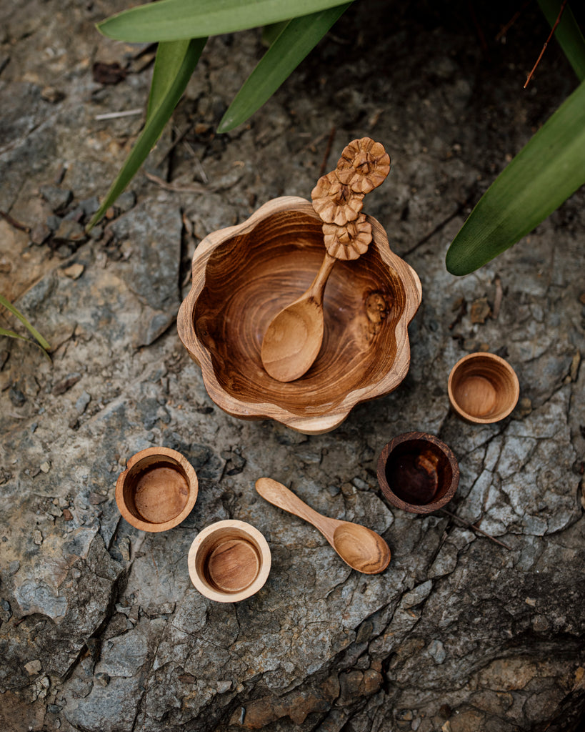birds eye view of a Wooden daisy bowl, flower spoon, mini pots and a mini spoon sitting on a slate rock