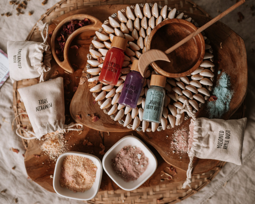 potion ingredients laid out on wooden board  with a wooden wand, & bowl 