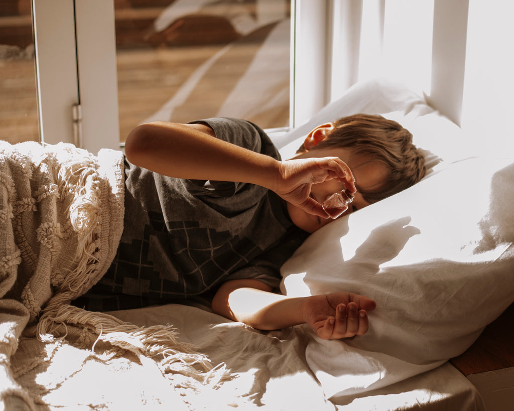 Child laying down in bed looking at a potion vial 